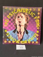 Front cover of The Psychedelic Furs Mirror Moves vinyl album showing fragmented portrait of lead singer with yellow stars and purple checkered background.