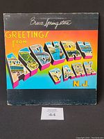 Front cover of Bruce Springsteen vinyl album Greetings from Asbury Park N.J. with colorful text and artwork.
