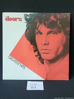 Front cover of The Doors Greatest Hits vinyl record album showing Jim Morrison's face in red and white design.