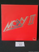 Front cover of the Moxy II vinyl record with red background and embossed silver text.