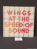 Front cover of the Wings At The Speed Of Sound vinyl record showing the album title in large colorful block letters on a white grid background.