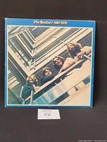 Front cover of The Beatles 1967-1970 album, showing the band members looking down from a balcony with a blue border and title text.