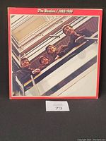 Front cover of The Beatles 1962-1966 album showing the band members leaning over a building railing in a vertical shot with a red border and white text.
