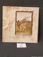 Front cover of vinyl showing significant peeling and discoloration around the edges. Image is of a man carrying a large bundle of sticks.