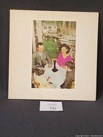 Front side of gatefold vinyl record cover featuring a family at a table near a marina.