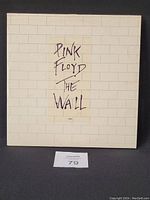 Front view of Pink Floyd The Wall vinyl album cover with white brick wall design and handwritten title.