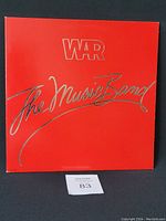 Front cover of the vinyl record showing red background with 'War The Music Band' in silver lettering.