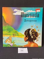 Front cover of the Massada Astaganaga vinyl record showing colorful tropical scene with woman, butterfly, and water.