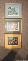 Three framed prints laid out vertically showing street scene, floral still life, and fruit lobster still life.