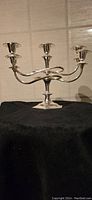 Front view showing full 5-candle metal candelabra with curved arms and solid base.