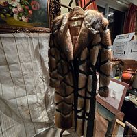 Full view of the vintage fur coat showing the long sleeve design and striped darker pattern on light brown fur.