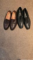 Two pairs of men's leather dress shoes on carpeted floor: brown Bodileys on left, black Giorgio Armani on right