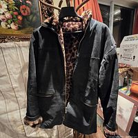 Front view of reversible winter coat showing black exterior and brown faux fur collar and sleeve cuffs.