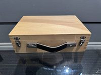 Closed wooden box with metal latches and black handle