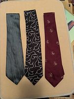 Three vintage Armani ties laid flat, showing full length and pattern of each tie.