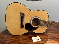 Close up of the guitar body showing sound hole, pickguard and bridge, illustrating the finish and strings.