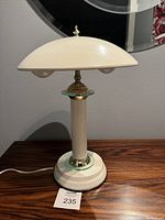 Full view of white metal mushroom-shaped touch lamp showing dome-shaped shade and cylindrical base with chrome accents on wood surface.