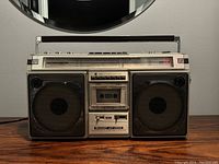 Front view of the Sharp GH-8686 boombox showing cassette tape compartment, speaker grills, and radio dial.