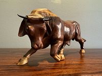 Front angle view of the wooden bull sculpture showing detailed carving and horns.