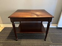 Front view of the vintage wooden side table showing wood grain and turned legs.