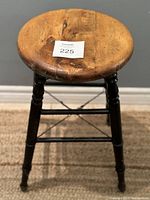 Front angle view showing round natural wood seat with metal support rods between legs.