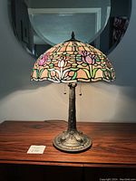 Full frontal view of lamp illuminated on wooden surface with mirror backdrop