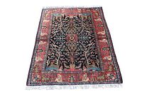 Full view of semi-antique Persian rug showing black field, border and fringes