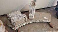 Photo showing curved cement bench seat slab with carved decorative front edge and two ornate pillar supports resting on top