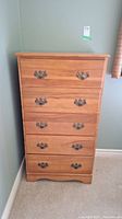 Front view of the five drawer dresser showing brass handles and wood grain finish