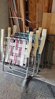 Three vintage folding lawn chairs stacked mostly folded showing nylon webbing and metal frames with plastic armrests