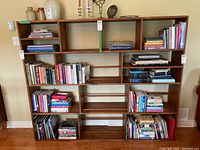 Full front view of vintage wood bookshelf with multiple cubicles filled with books and a few decorative items on the top shelf.