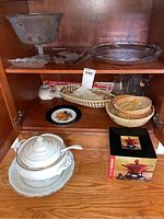 Overview of soup tureen, fondue set, bread baskets, and serving dishes on wooden shelving.
