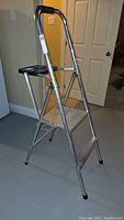 Side view of two-step aluminum painter's ladder showing black grip handle, steps and platform with paint tray holder