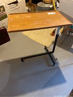 Full side view of rolling tray table showing wooden surface, metal frame with three wheels, and base support.