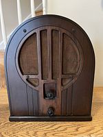 Front view of the antique Philco table radio showing the two control knobs and cloth-covered speaker grille on the wooden cabinet.