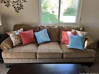Front view of beige upholstered sofa with six throw pillows