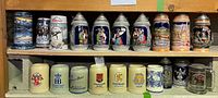 Photo of two shelves with multiple beer steins and mugs showing a variety of styles and logos