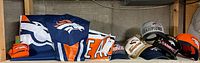 Shelf with several Denver Broncos hats, flags, and orange socks visible