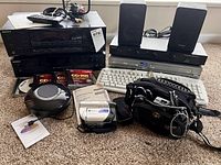 Front view of the electronics lot showing Sony CD player, miniDisc deck, 5-CD changer system, speakers, camcorder, cables, and CDs