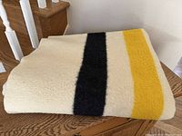 Folded wool blanket showing the yellow and black stripes on cream background.