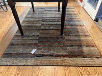 Full view of kitchen rug with table legs over it, showing size and pattern.