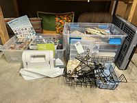 Wide view showing containers with quilting supplies, metal racks, and folded pillows on floor in storage area