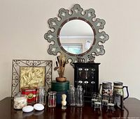 Full view of vintage home decor on wooden surface including wall mirror, Polish pottery, candle holders, jars, tins and art pieces
