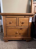 Front view of one Woodley's pine nightstand showing three drawers and natural wood finish.