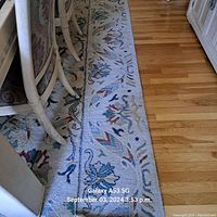 Close view of the rug showing its border design with floral and leaf motifs in various colors.