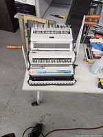 Full front view of the Akiles WireMac Combo binding machine showing the punch handle and comb/wire binding slots