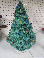 Front view of green ceramic Christmas tree with attached colored bulbs and power cord.