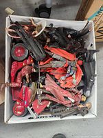 Top-down view of cardboard box with assorted action figures and red motorcycle.