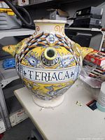 Front and side view of the large colorful ceramic pot showing detailed dragon handles and floral painted decoration along with 'TERIACA' inscription.