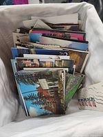 Top view of a box full of assorted travel postcards, showing various images of landscapes and landmarks
